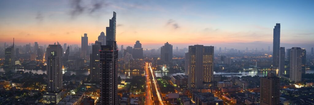 A city skyline at dusk with lit high-rise buildings.