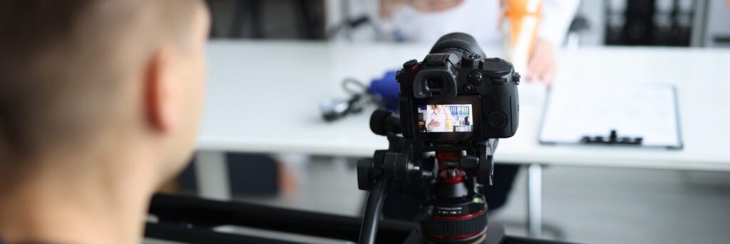 A camera on a tripod filming a healthcare professional during a video shoot.